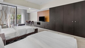Une chambre d’hôtel moderne équipée de deux lits, d’une télévision, d’un bureau et d’une grande armoire.