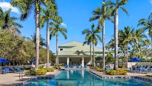 A pool area with lounge chairs and palm trees.