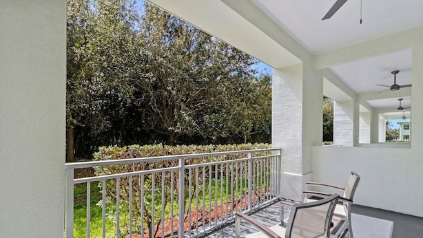 A balcony with a metal railing, a table, and two chairs.