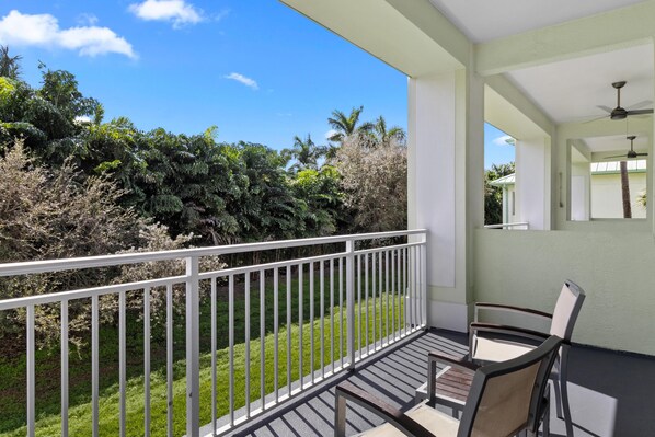 A balcony with a white railing, a table, and two chairs.