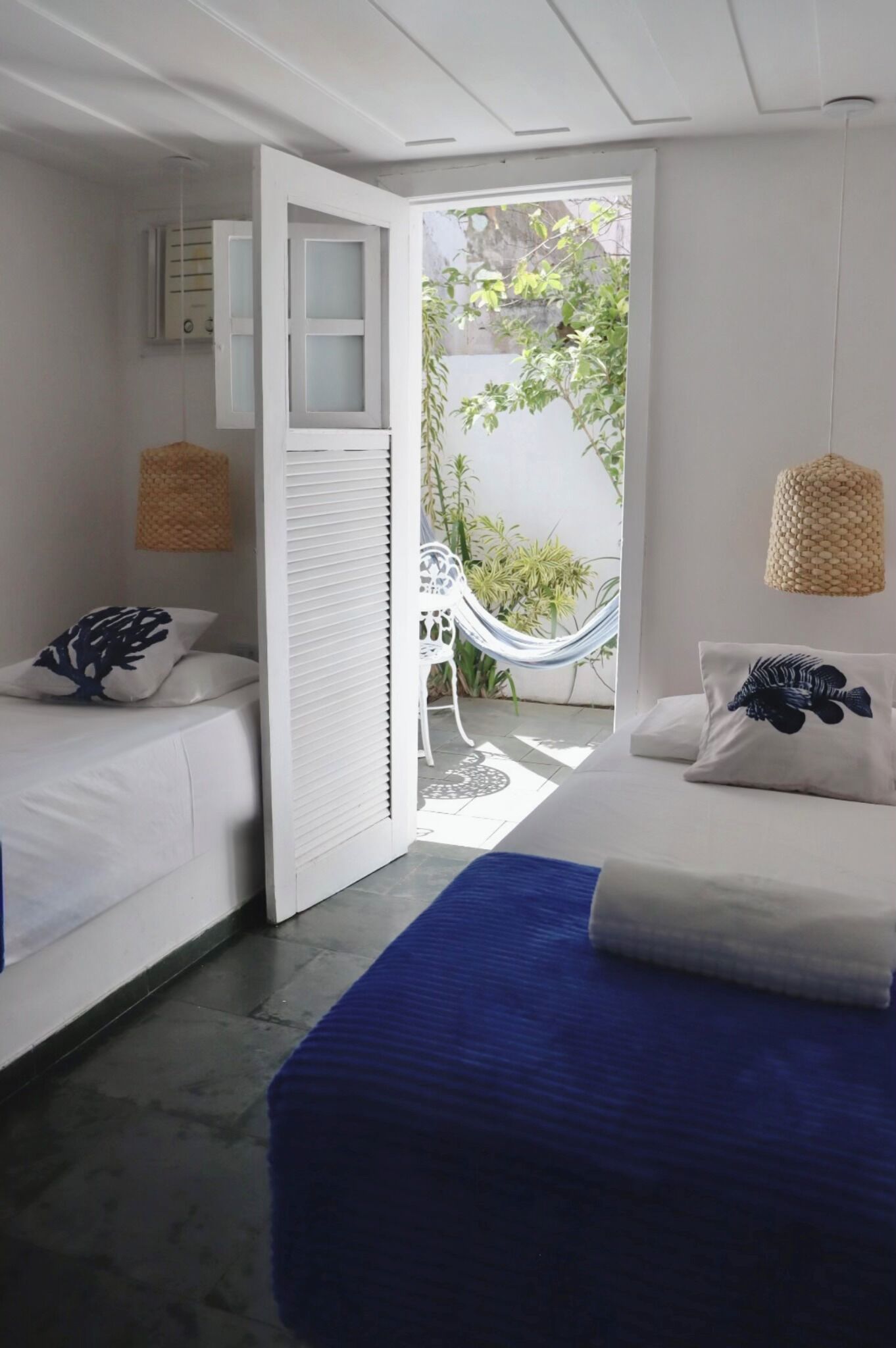 A bedroom with two beds, a hammock, and a view of the outdoors.