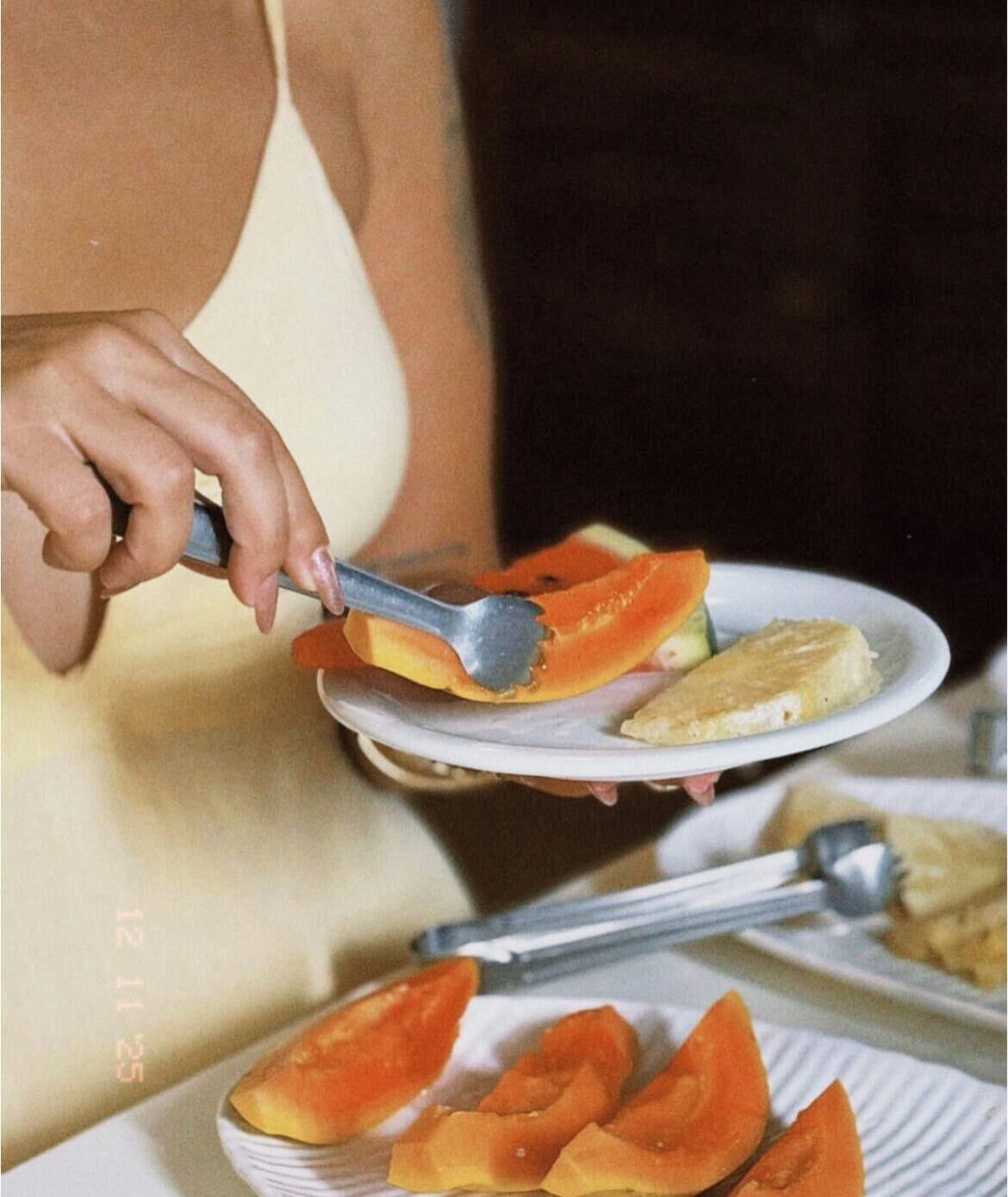 Een persoon houdt een bord eten vast, met een stuk fruit en een sneetje brood.