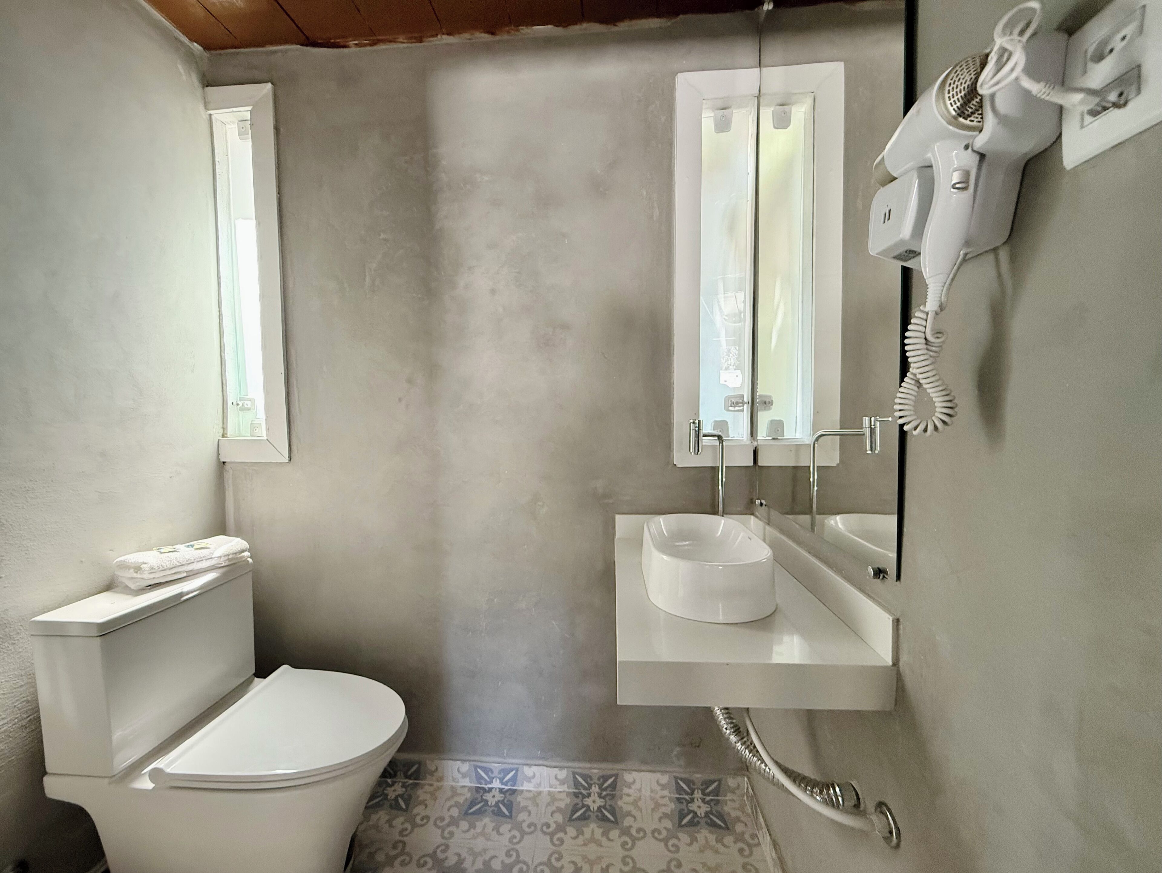A small bathroom with a toilet, a sink, and a hairdryer mounted on the wall.