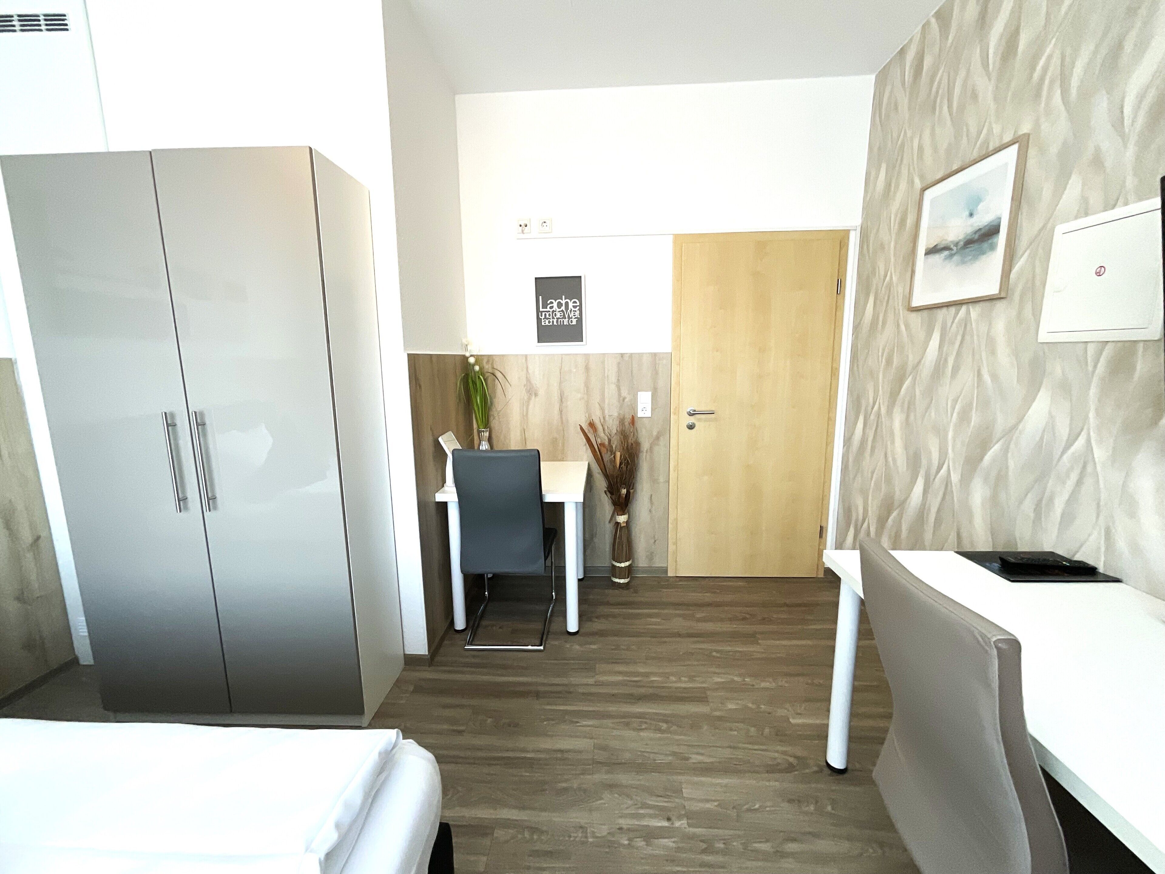 Une chambre d’hôtel moderne équipée d’un lit, d’un bureau, d’une chaise, d’une armoire et d’une porte.