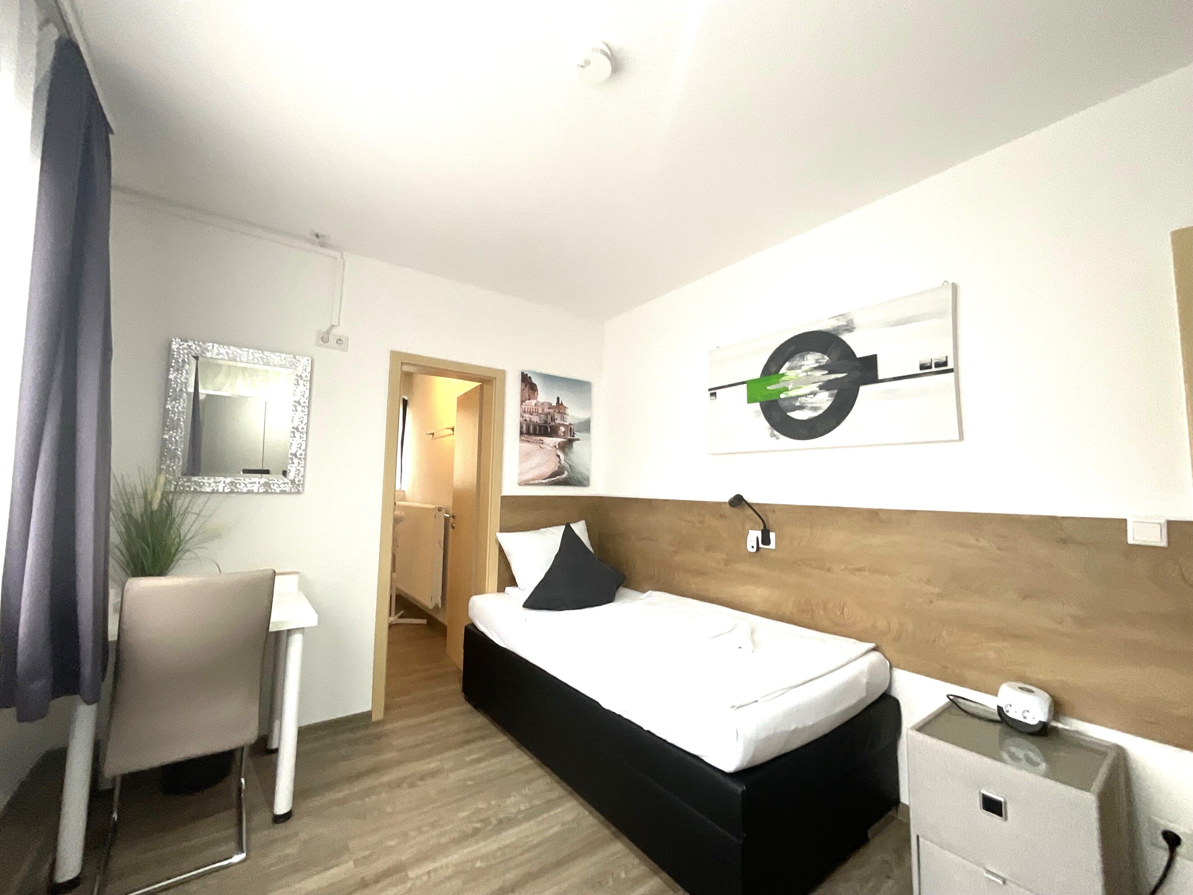 Ein Hotelzimmer mit Bett, Nachttisch, Stuhl und Schreibtisch.