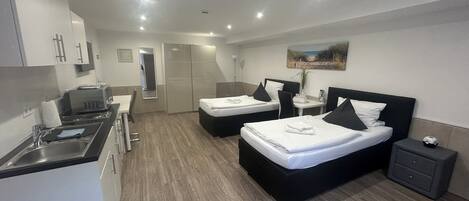 Una habitación de hotel moderna con dos camas, una kitchenette, un baño y un pequeño comedor.