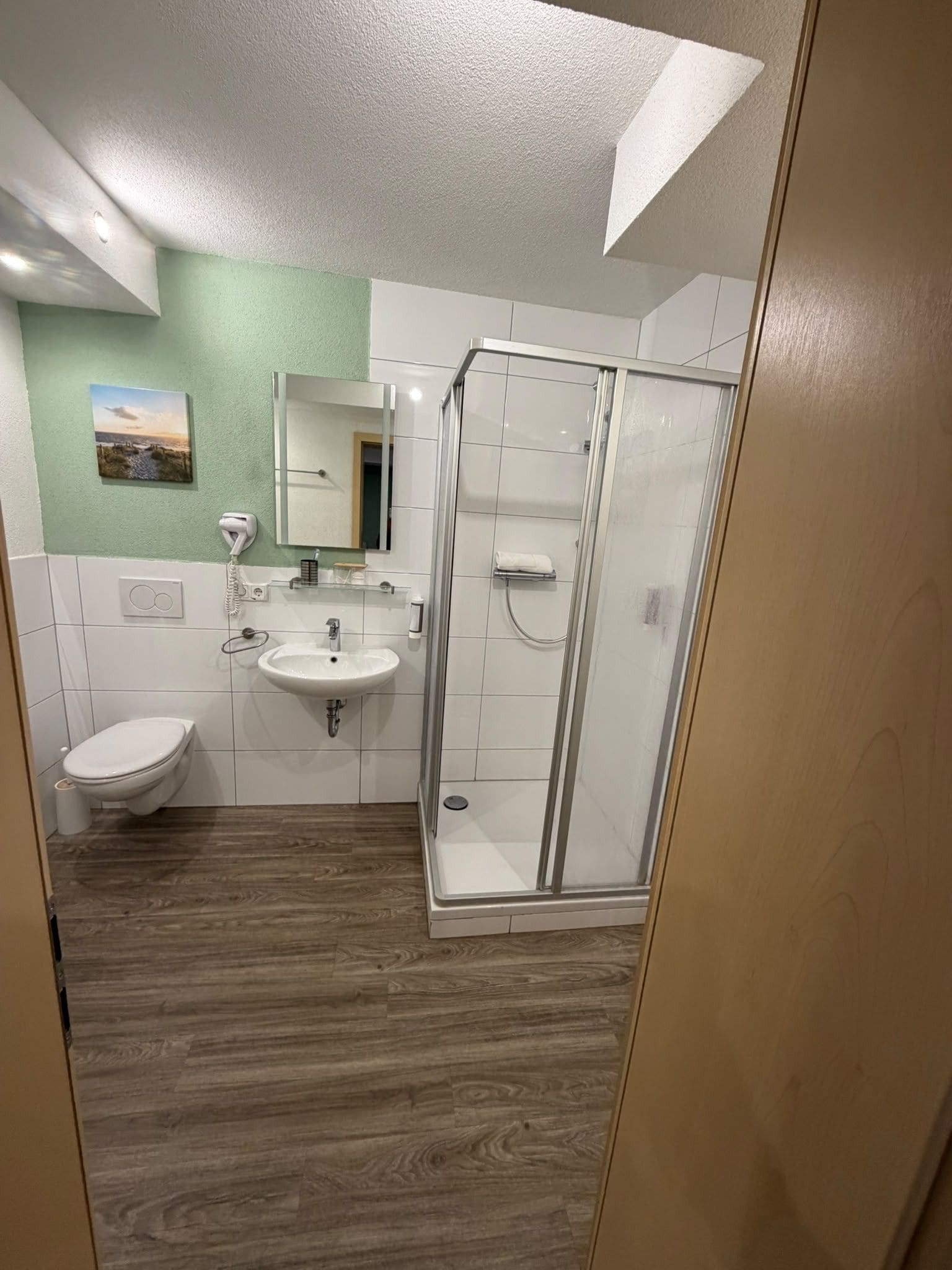 A bathroom with a toilet, sink, and glass shower enclosure.