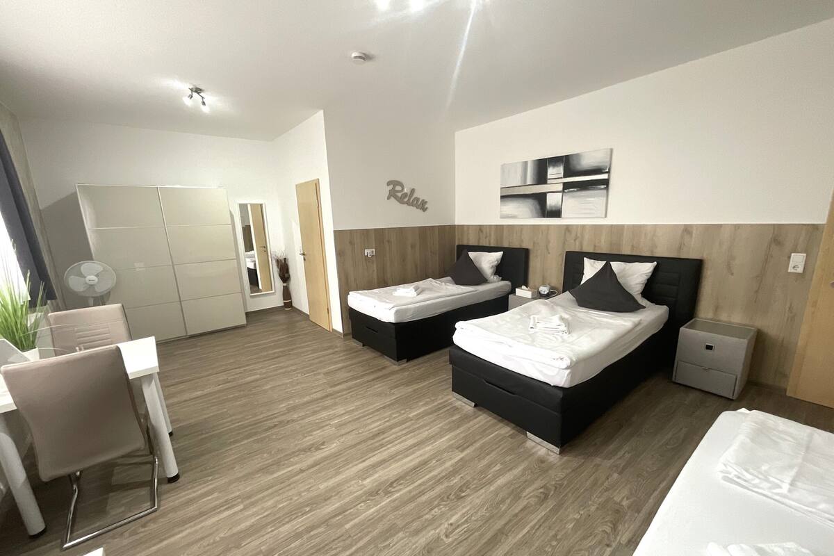 Une chambre d’hôtel moderne avec deux lits, un bureau et une chaise.