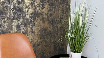 A brown leather chair next to a small round table with a potted plant and a wooden block with the word "love".