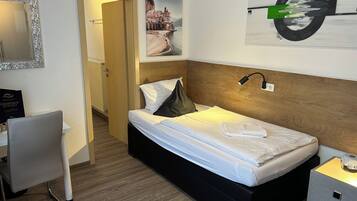 Een hotelkamer met een bed, een bureau, een stoel, een nachtkastje en een schilderij aan de muur.