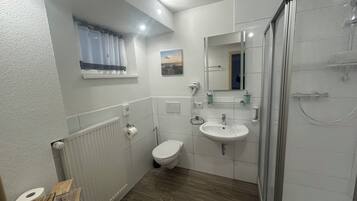 Un baño moderno con inodoro, lavamanos y ducha.