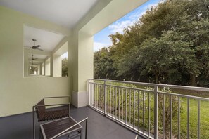 A balcony with a metal railing, a bench, and a ceiling fan.
