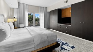 A modern hotel room with a large bed, a TV, dark cabinets, and a balcony with a view. - 3 Bedroom/4 Bath Townhouse, Pool, Parking, & More! (Miami)