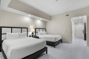 A hotel room with two beds, a nightstand with a lamp, and a door leading to a hallway. - Paradise Retreat | King Suite w/ Kitchen (Miami)