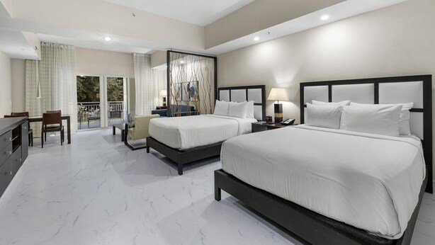 A hotel room with two beds, a dining area, and a balcony with curtains. - Paradise Retreat | King Suite w/ Kitchen (Miami)
