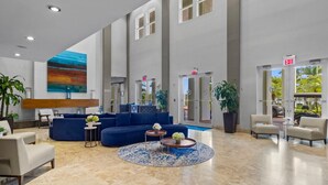 A spacious lobby with a blue sofa, a round coffee table, and a large painting on the wall. - Paradise Retreat | King Suite w/ Kitchen (Miami)