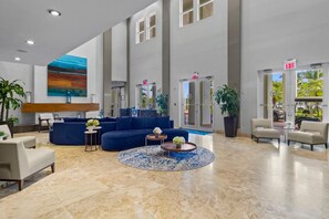 A spacious lobby with a blue sofa, a round coffee table, and a large painting on the wall. - Paradise Retreat | King Suite w/ Kitchen (Miami)
