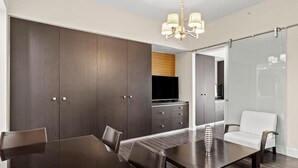 A modern dining area with a dark wood table, chairs, and a chandelier.