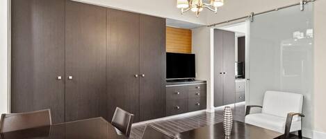 Un comedor moderno con una mesa de madera oscura, sillas y una araña.