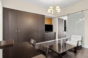 A modern dining area with a dark wood table, chairs, and a chandelier.