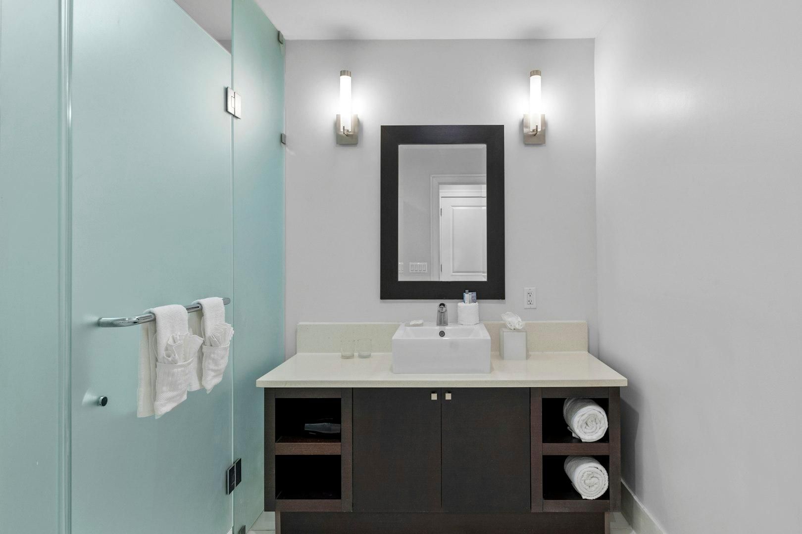 Een badkamer met een wit wastafelmeubel, een spiegel en twee handdoekrekken.