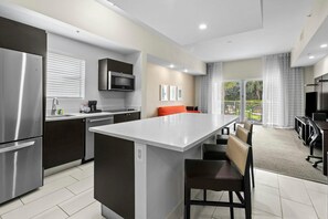 A modern kitchen with a central island, stainless steel appliances, and a dining area with a view. - Enjoy Shopping, Dining, Golfing - King Studio XL (Miami)