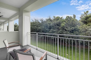 A balcony with a white railing, a chair, and a table.