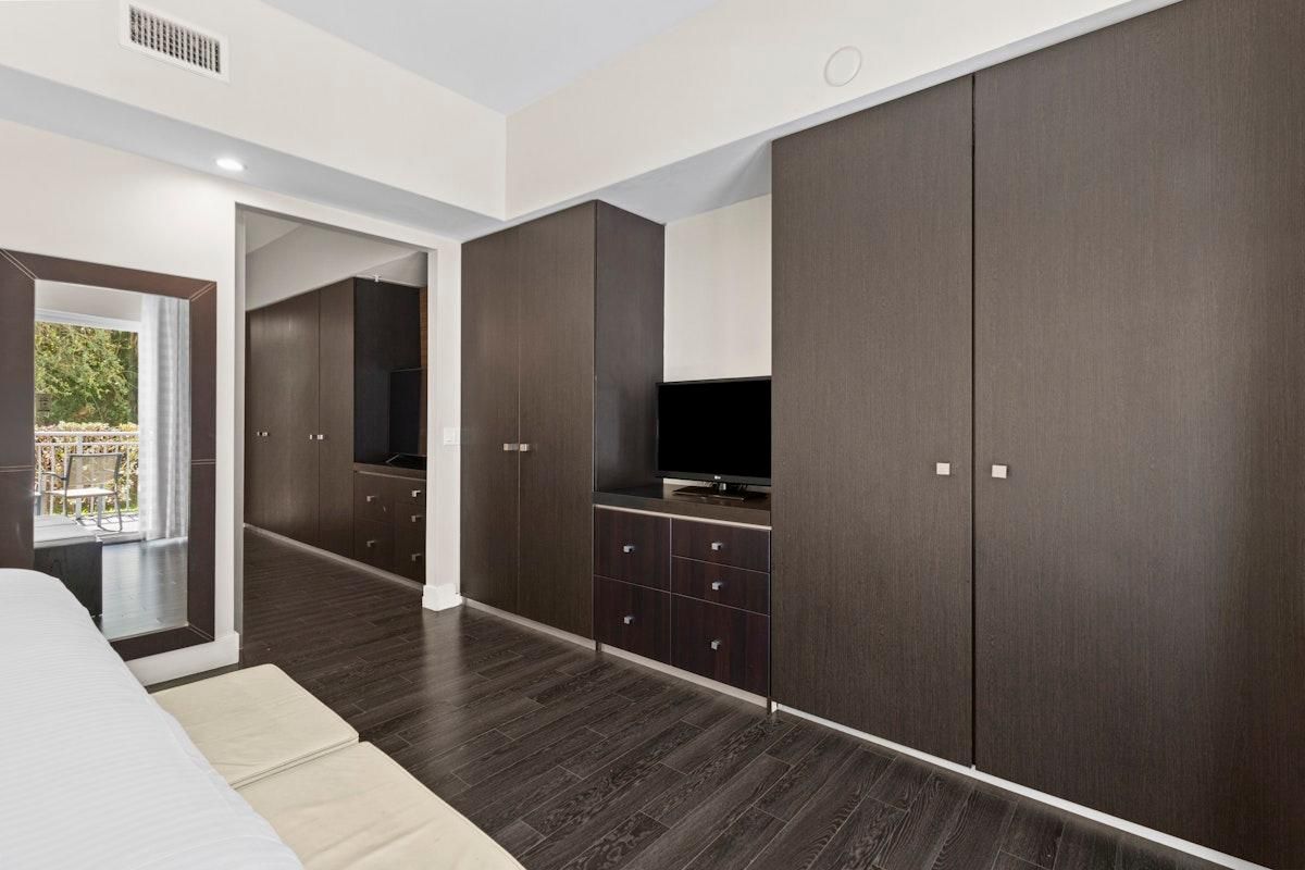 A modern bedroom with a large wardrobe, a television, and a balcony view.