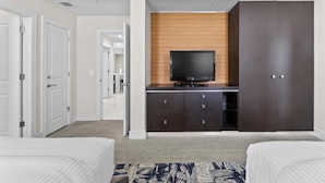 A hotel room with a bed, a TV on a wooden cabinet, a wardrobe, and a carpeted floor.