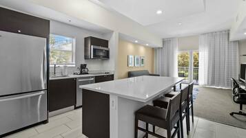 A modern kitchen with a central island, stainless steel appliances, and a dining area with a TV.