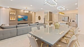 A modern kitchen with white cabinets, a large island, and stainless steel appliances. - 12BR house with private pool in Paradiso Grande (Orlando)