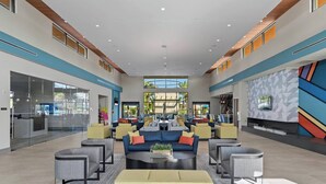A spacious lobby with a central seating area, a reception desk, and a large window offering a view of the outdoors. - 12BR house with private pool in Paradiso Grande (Orlando)