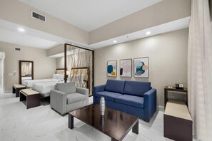 A modern hotel room with a bed, a sofa, a coffee table, and artwork on the wall. - Doral Studio – enjoy Shopping, Dining, Golfing (Miami)