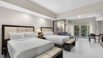 A hotel room with two beds, a balcony, and a dining area.