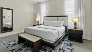 A hotel room with a large bed, two bedside tables with lamps, a bench, and a large mirror on the wall. - King Studio Oasis | Room to Relax (Miami)