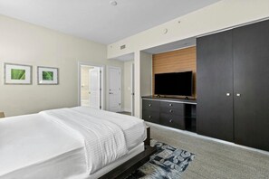 A bedroom with a bed, a wardrobe, a television, and a door leading to another room.