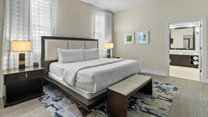 A hotel room with a bed, bedside tables, a bench, a rug, and a bathroom visible through an open door. - King Studio Oasis | Room to Relax (Miami)