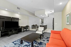 A modern living room with a flat-screen TV, a coffee table, and a sofa.