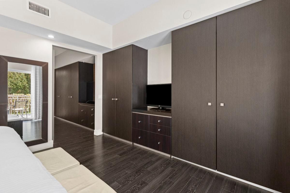 Et moderne soveværelse med stor garderobe, fjernsyn og balkonudsigt.