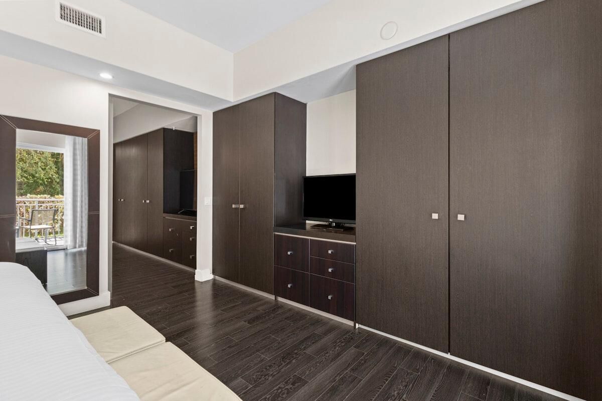 Un dormitorio moderno con un armario grande, televisión y vistas al balcón.