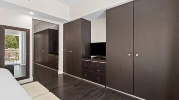 Un dormitorio moderno con un armario grande, televisión y vistas al balcón.