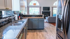 Une cuisine moderne dotée de plans de travail en granit, d’appareils électroménagers en acier inoxydable et d’un grand îlot central avec un évier.