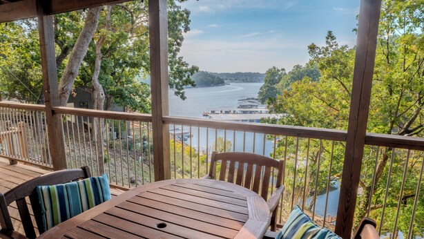 Une terrasse en bois avec une table et des chaises, donnant sur une rivière et des arbres.