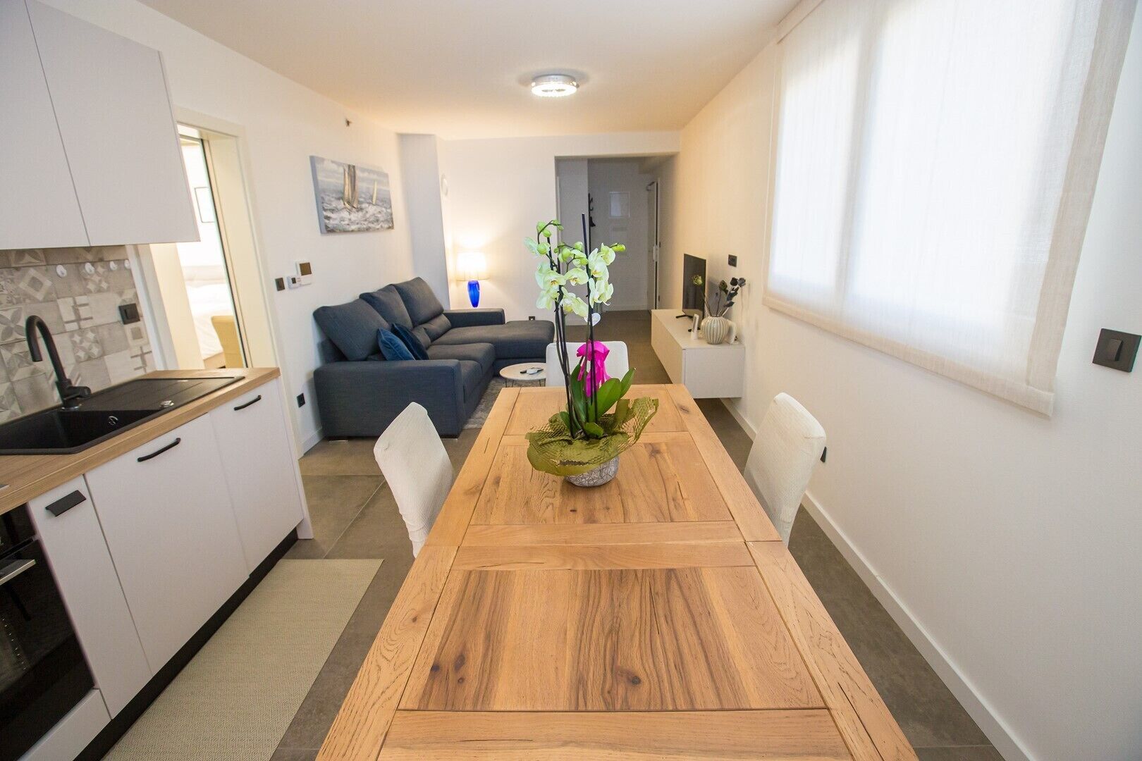 A modern kitchen with white cabinets and a wooden dining table.