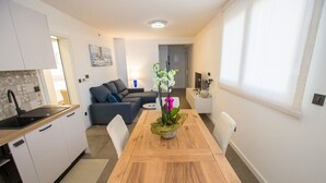 A modern kitchen with white cabinets and a wooden dining table. - Apartman Sonia in Porec (Porec)