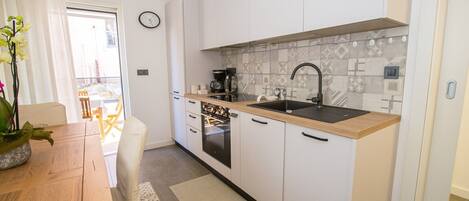 A modern kitchen with white cabinets, a wooden countertop, a black sink, and a patterned backsplash.