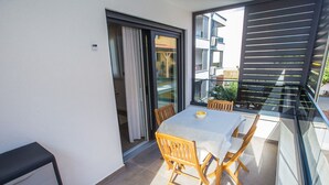 A balcony with a table and chairs, a sliding glass door, and a view of a building with balconies. - Apartman Sonia in Porec (Porec)
