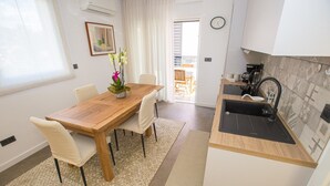 A modern kitchen with a wooden table and chairs, a small sink, and a view to the outside. - Apartman Sonia in Porec (Porec)