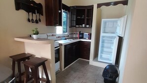 Una cocina con isla central, armarios de madera oscura, microondas y refrigerador.