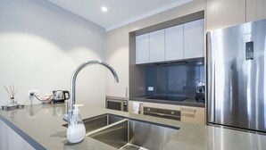 Una cocina moderna con electrodomésticos de acero inoxidable, horno empotrado y un grifo elegante.